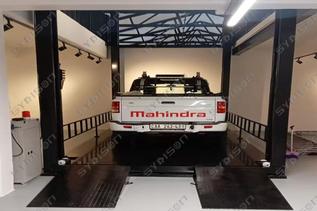 Heavy-duty Syrison FPL series four post car elevator floor lifting platform installed in a multi-story commercial showroom.