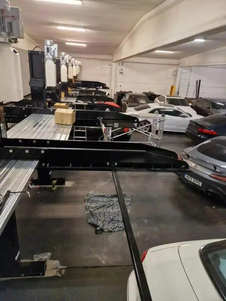 On-site installation process of 9 connected interlocking two-post car parking lifts using shared columns.